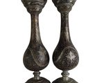 two metal vases sitting on top of each other on a white surface