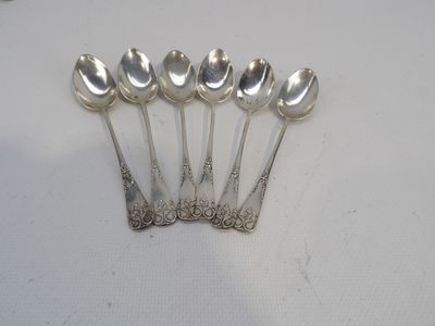 six cuillères en argent sont alignées sur une surface blanche