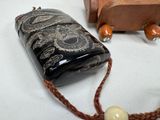 a black bottle with a white bead on a string