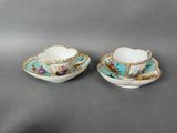 a pair of tea cups and saucers decorated with flowers