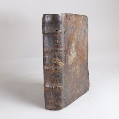 un vieux livre posé sur une table blanche à côté d'un mur blanc