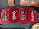 three silver figurines of women in red velvet cases on a table