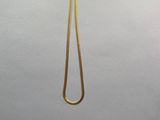 un collier en or dont l'extrémité est ornée d'une longue chaîne