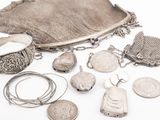 an assortment of silver jewelry including a purse, bracelets, and a coin