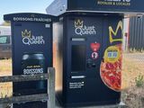 two vending machines that have pizzas on them in front of a fence