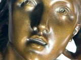 a bronze statue of a woman with a hat on her head