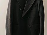 un manteau en laine noir suspendu à un cintre sur un mur blanc