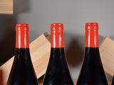 three bottles of red wine sit on a table in front of a wooden box