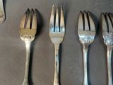 six forks and spoons are lined up on a table