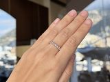 a woman ' s hand holding a diamond ring in front of a window