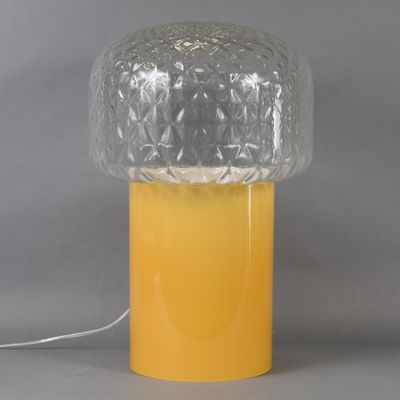a yellow table lamp with a clear glass shade on top of it