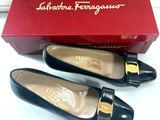 une paire de chaussures noires dans une boîte rouge posée sur une surface blanche