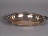 an antique silver plate with a handle and handles on a gray surface