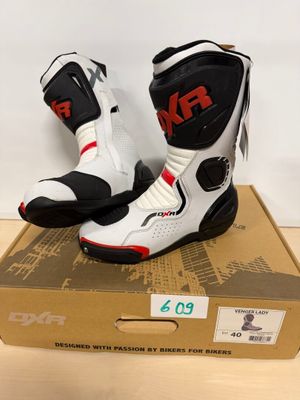 une paire de bottes de moto blanches et noires posées sur une boîte en carton