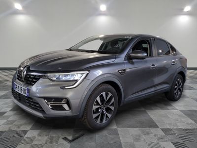une voiture grise est garée dans une grande pièce au sol en damier