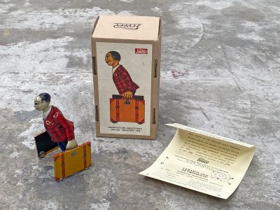 une petite figurine représentant un homme avec une valise, à côté d'une boîte contenant des bagages