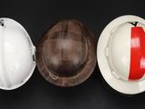 three hard hats and a hard hat are lined up on a black surface