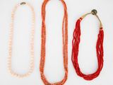 trois colliers composés de perles rouges et orange sur fond blanc
