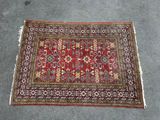 a red rug with a floral design on a grey floor