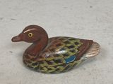 a small wooden duck that is sitting on the ground