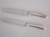 two silver plated knives with a handle and a knife on a white surface