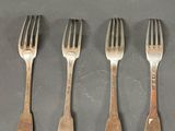 quatre fourchettes sont disposées en rangée sur une table