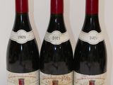 trois bouteilles de vin rouge sont alignées sur une table