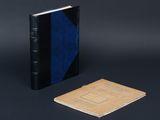 un vieux livre posé à côté d'un petit carnet sur une surface noire