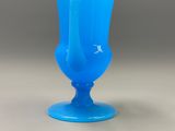 a blue glass vase sitting on top of a table