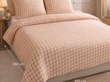 the bed is made up with a checkered comforter and pillows