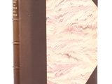 un vieux livre à la couverture brune posé sur une surface blanche