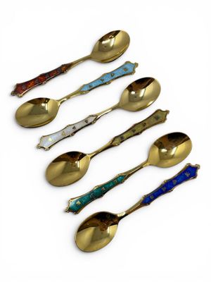 six spoons and a spoon rest in a row on a white surface