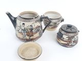 a tea pot and two cups with a tea strainer next to it