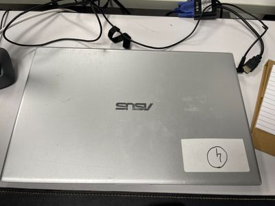 un ordinateur portable posé sur un bureau, à côté d'un bloc-notes