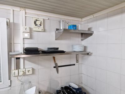 a small kitchen with a sink, stove, and shelves