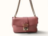 un sac à main rose muni d'une bandoulière en chaîne et d'un fermoir sur le devant