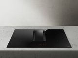 a black stove top sitting on top of a counter next to a wall