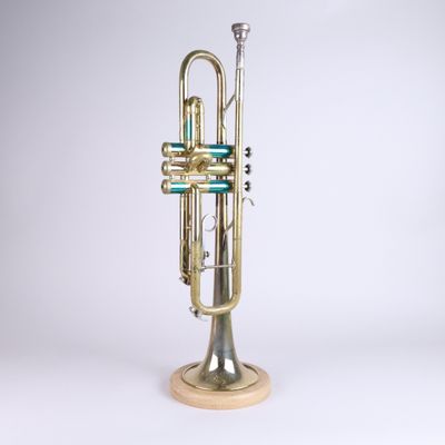 an old brass trumpet on a wooden stand against a white background
