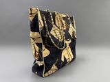 the black and gold bag is sitting on a gray surface