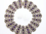un gros plan d'un collier violet et vert posé sur une surface blanche