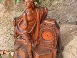 une statue représentant un homme assis sur une chaise à côté d'une horloge