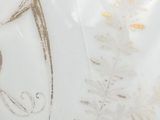 a white bowl with gold decoration on it on a table