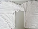 two white t - shirts sitting on top of a table next to each other