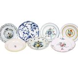 de nombreuses assiettes aux motifs variés, disposées sur un fond blanc