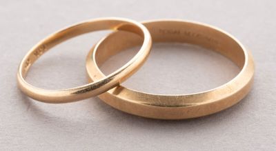 two gold wedding rings sitting on top of each other on a table