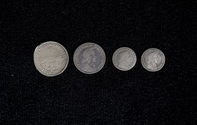 four different coins are shown in a row on a black surface