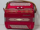 an image of a red accordion sitting on top of a white table