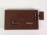 a close up of a brown electronic device on a white surface