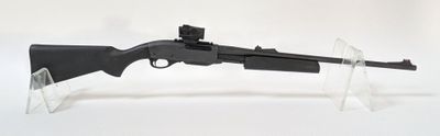 un pistolet jouet posé sur un socle transparent, sur une surface blanche