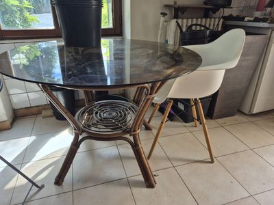 une table en verre sur laquelle se trouvent deux chaises et un vase